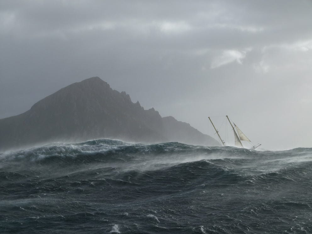 Cape Horn with sailboat under large waves